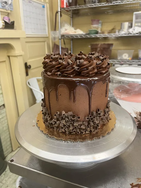 Chocolate cake with a glossy drip, piped chocolate rosettes, and chocolate shavings.