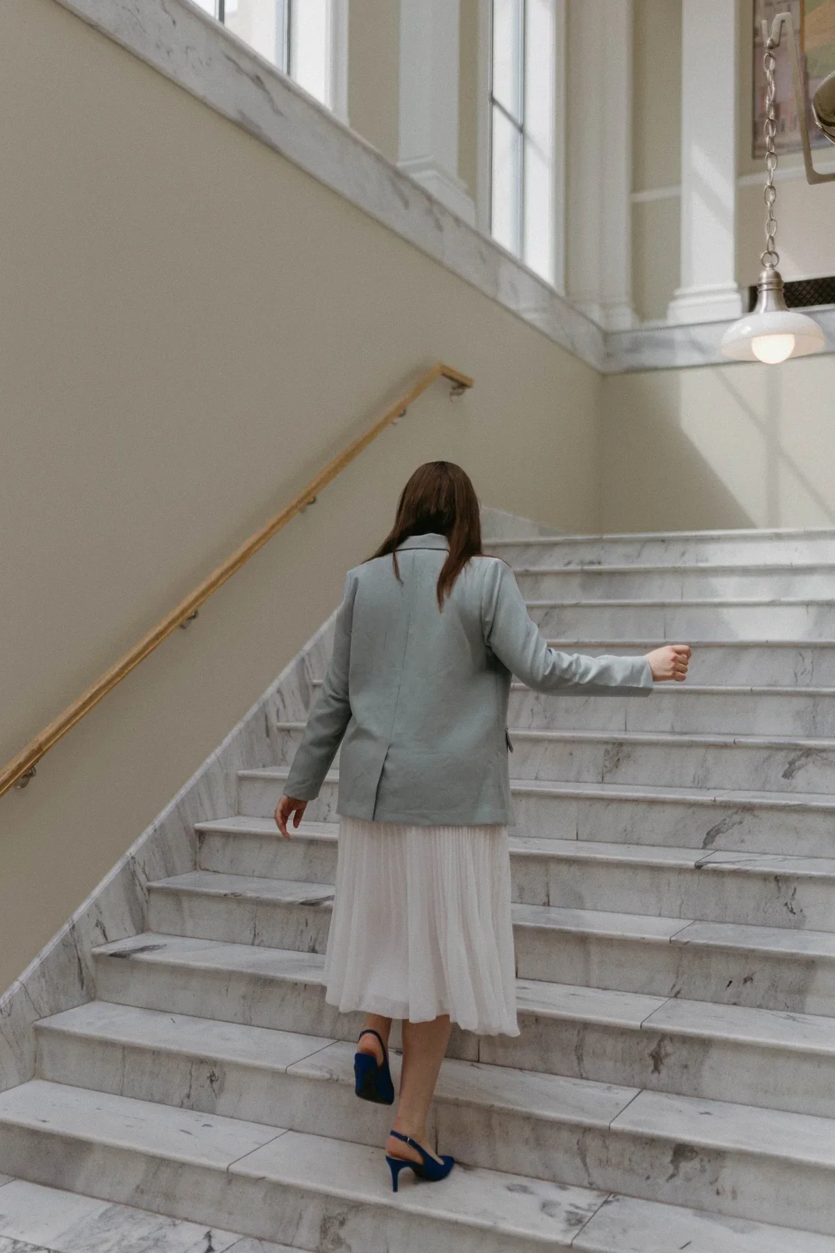 Selena walking up a broad staircase.